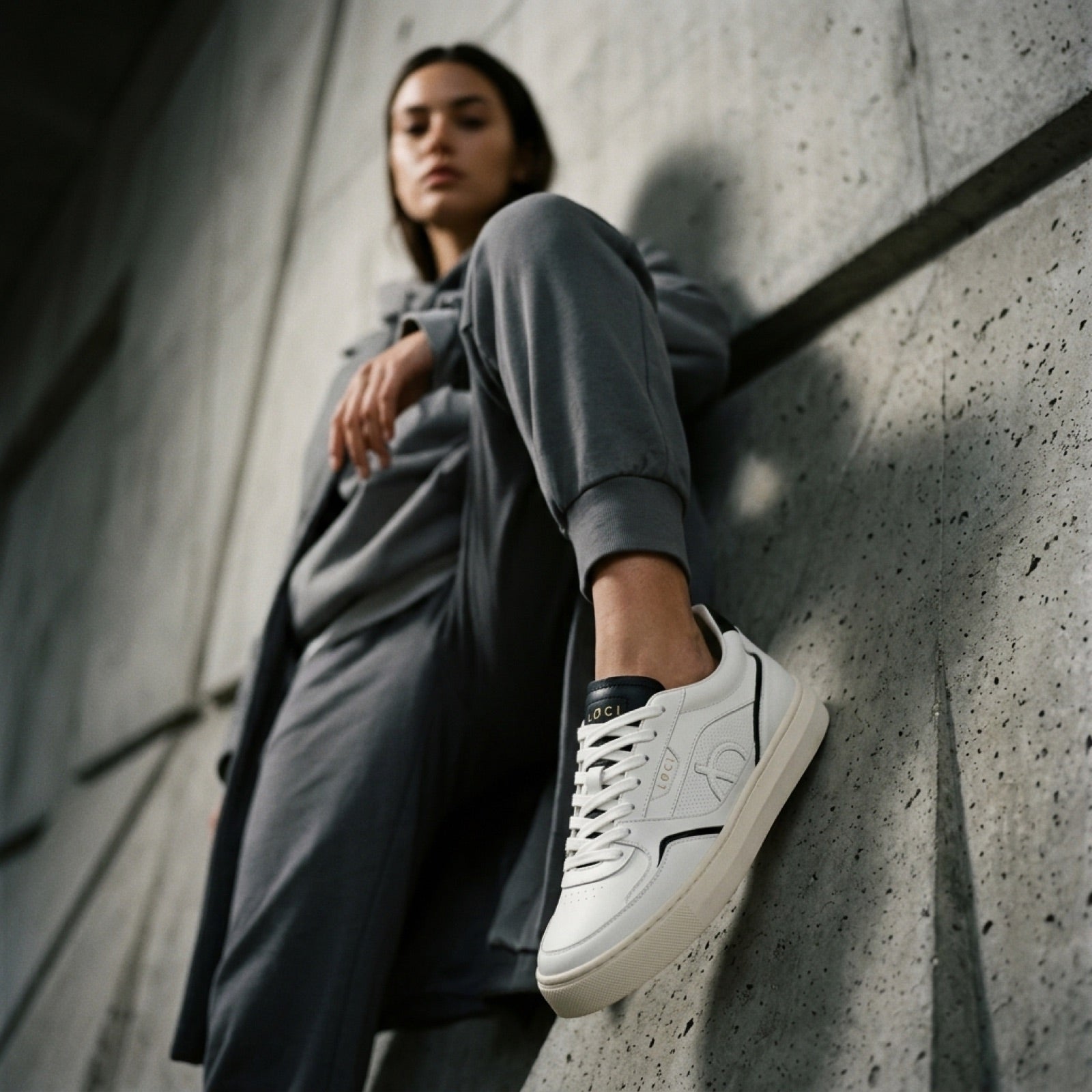 LØCI sneaker and charcoal layers photographed against concrete
