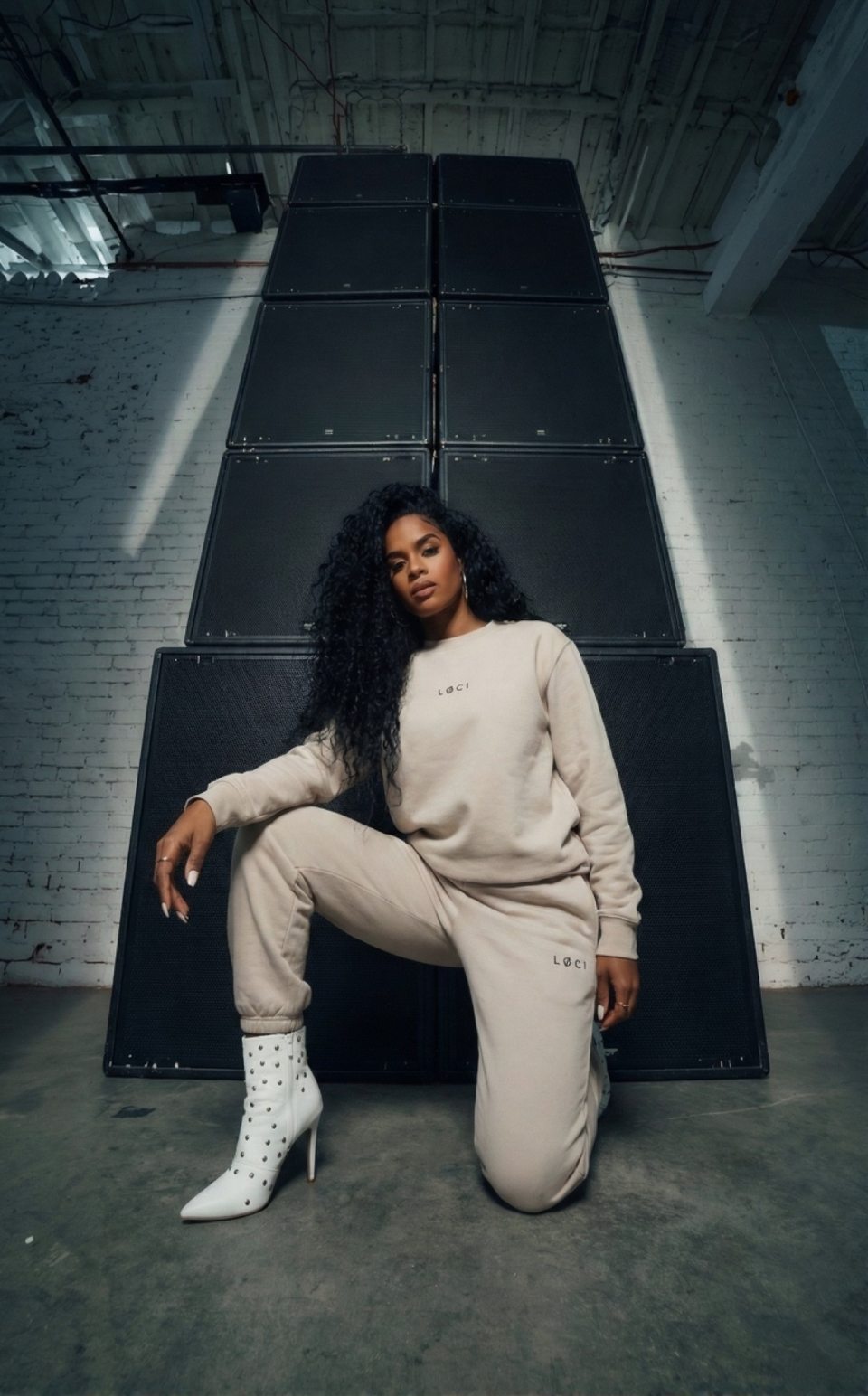 LØCI cream matching sweatshirt and trousers worn beside a speaker stack